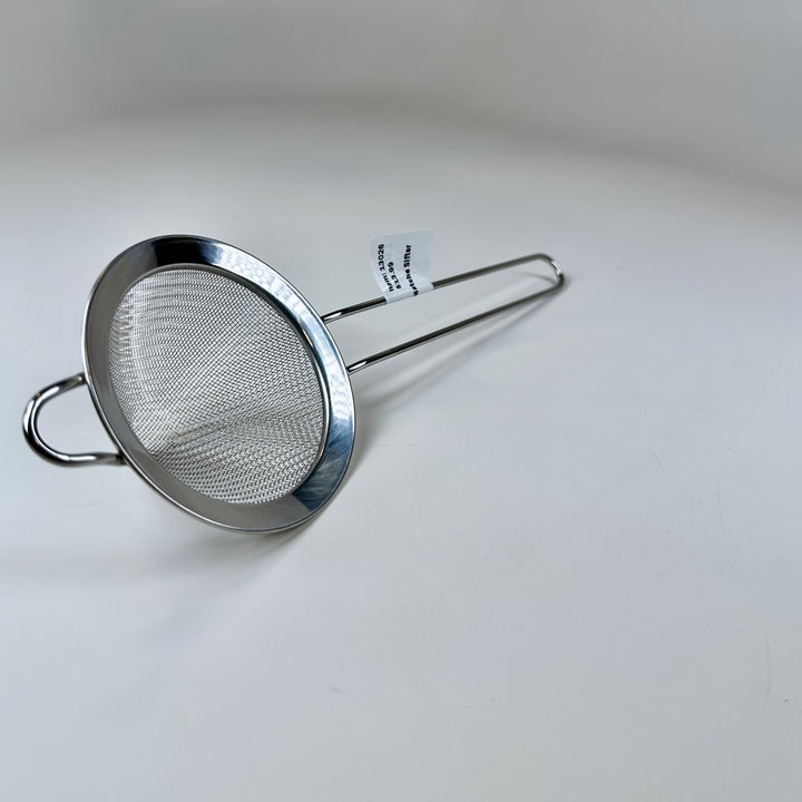 Fine-mesh stainless steel matcha sifter with wooden spatula for smoothing matcha powder.